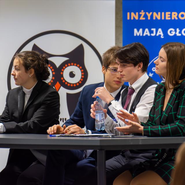 czwórka uczestników debaty na tle baneru koła naukowego