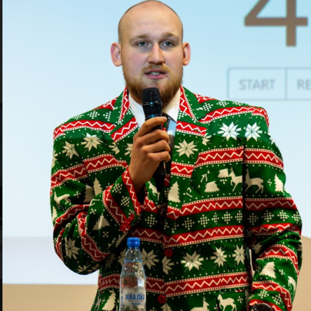 prowadzący dyskusję w kolorowej świątecznej marynarce