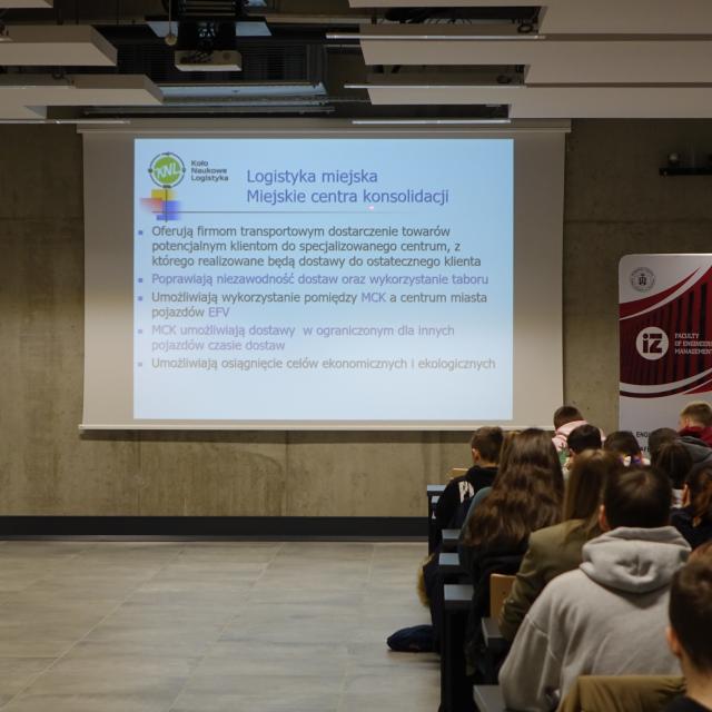 Uczetsnicy słuchający wykładu i prelegent z prezentacją - Aula