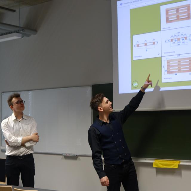 Dwóch studentów prezentujących projekt na ekranie.